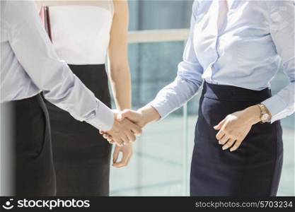 Midsection of businesswomen shaking hands in office