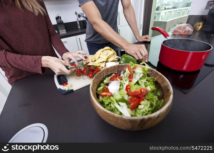 Midsection of couple cooking together at kitchen counter