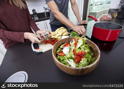 Midsection of couple cooking together at kitchen counter
