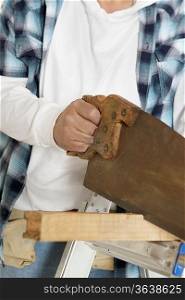 Midsection of male construction worker cutting wood with handsaw