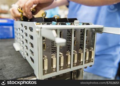 Midsection of male engineer repairing video card at table in electronics industry