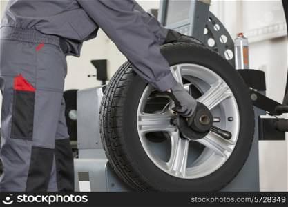 Midsection of male mechanic repairing car&rsquo;s wheel in repair shop