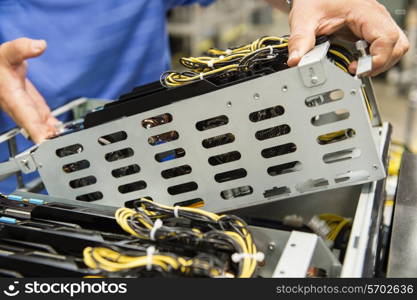 Midsection of male technician examining video card in computer manufacturing industry