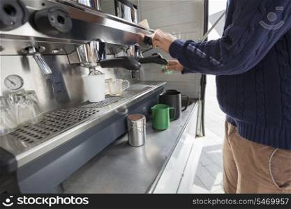 Midsection of man cleaning coffee machine at mobile shop