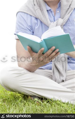 Midsection of man holding book in park