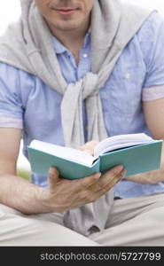 Midsection of man holding book in park