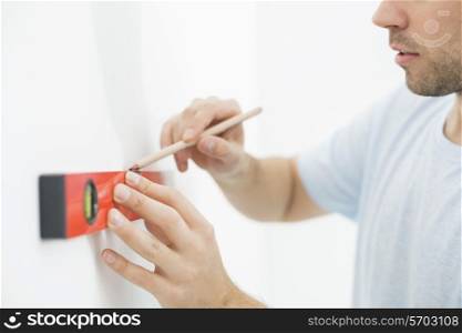 Midsection of man marking on wall with level