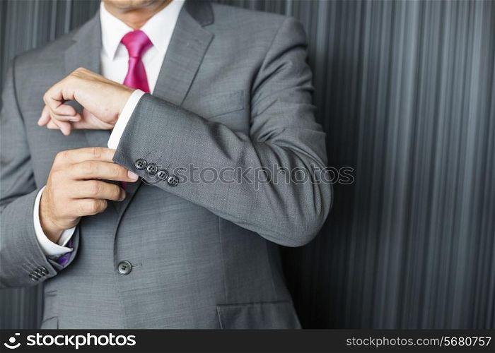Midsection of mature businessman buttoning sleeve