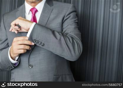 Midsection of mature businessman buttoning sleeve