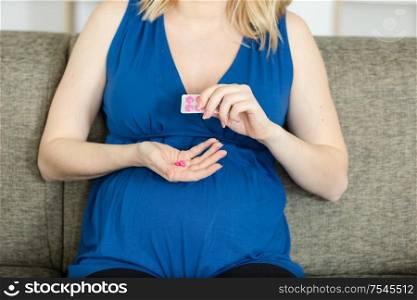 midsection of pregnant woman taking medicine at home