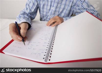 Midsection of senior businessman writing in file at desk