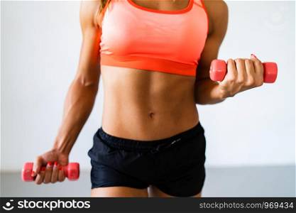 Midsection of sporty fit sportswoman doing biceps curls with dumbbells at the training workout aerobic pose muscular isolated on white background