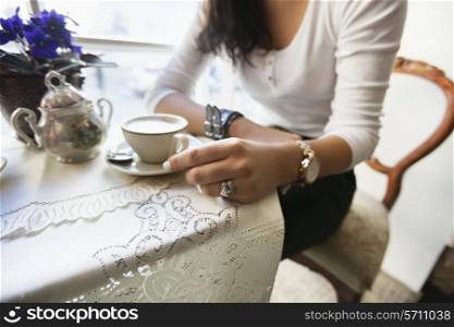 Midsection of woman having coffee at cafe