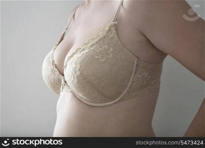 Midsection of woman in bra over gray background