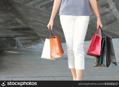 Midsection of woman walking out from department store carrying shopping bags