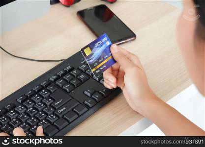 midsection of woman with credit card book bank and calculator paying bills online indoor