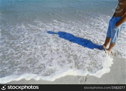 Midsection view of a man standing in the water on the beach
