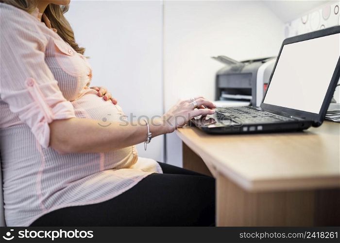 midsection view pregnant woman using laptop wooden desk