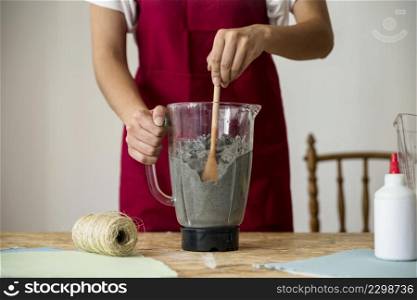midsection view woman s hand stirring paper pulp blender