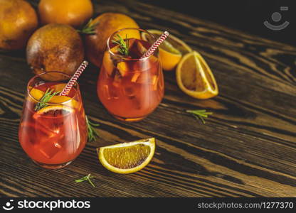 Milano spritzer alcoholic cocktail with red bitter, dry white wine, soda, red orange and ice. Dark wooden background, selective focus