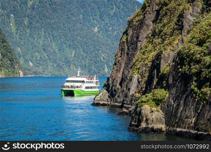 "MILFORD SOUND, NEW ZEALAND - DECEMBER 8, 2016: Tour boat cruises out into Milford Sound in Fiordland National Park. Milford Sound was described as "the eight wonder of the world" by Rudyard Kipling."