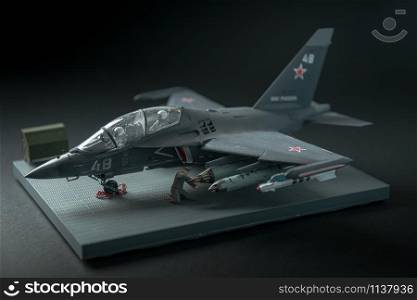 military fighter on a black background with place for text. On the tail of the plane is a red star of the Soviet army. RUSSIA / YAK-130 - 2019. Miniature of military fighter on a black background with place for text