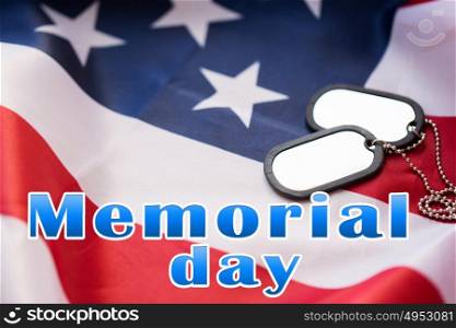 military forces, patriotism and national holidays concept - memorial day words over american flag and soldiers badges. memorial day words over american flag and dog tags