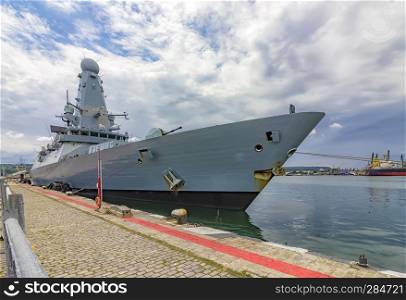 Military navy ship in port. Military sea landscape with cloudy sky at sunset