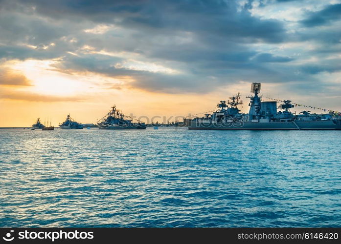 Military navy ships in a sea bay at sunset time