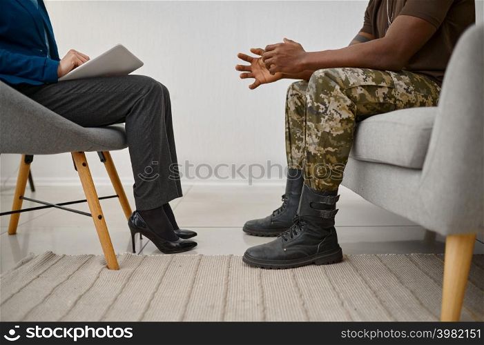 Military patient sitting front of psychologist. Cropped shot. PTSD psychological trauma treatment. Military male patient sitting front of psychologist