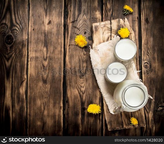 Milk and dandelion flowers on the Board. On a wooden table.. Milk and dandelion flowers on the Board.