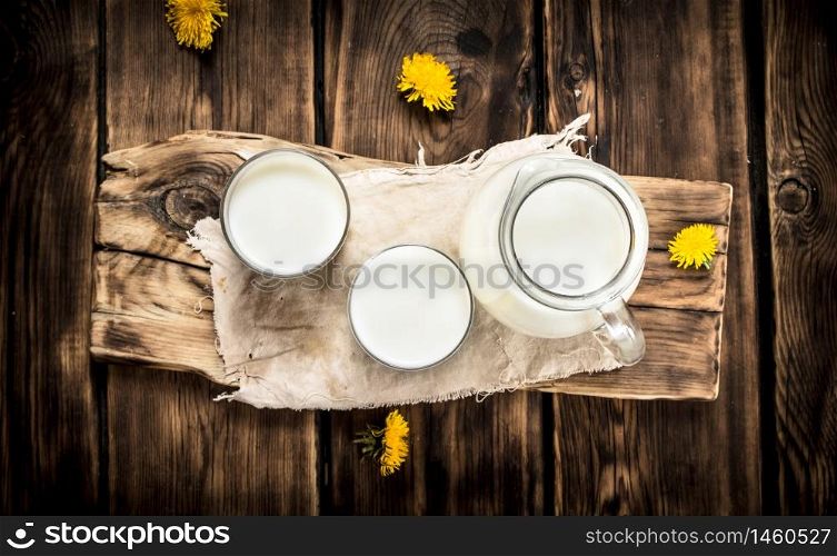 Milk and dandelion flowers on the Board. On a wooden table.. Milk and dandelion flowers on the Board.