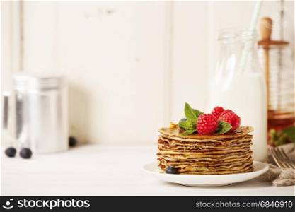 Milk and Stack of pancakes topped with berries and honey. Milk and pancakes
