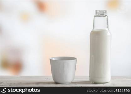 Milk bottle and a cup on a wooden table