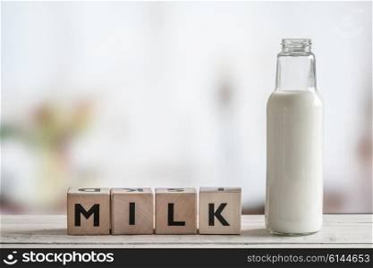 Milk bottle and the word milk on a wooden table
