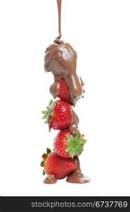 Milk chocolate being poured over a stack of strawberries.
