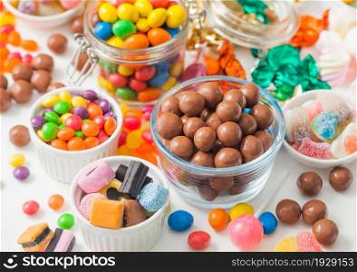Milk chocolate candies in shell with jelly sugar gums and liquorice allsorts and fruit sherbet candies on white background. with marshmallows and strawberry bon bons.