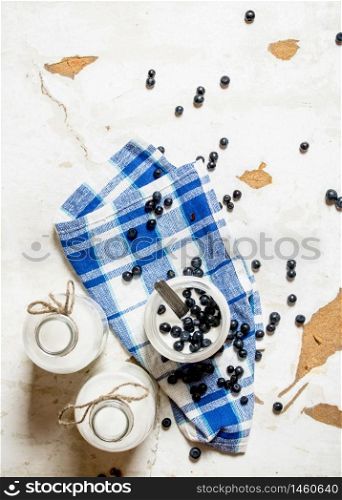 Milk cream in a jar with blueberries on the fabric. On rustic background.. Milk cream in a jar with blueberries on the fabric.
