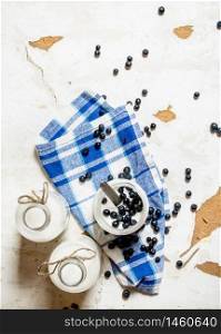 Milk cream in a jar with blueberries on the fabric. On rustic background.. Milk cream in a jar with blueberries on the fabric.