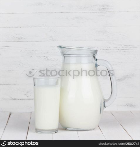 Milk glass and jar on white wooden table