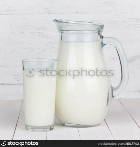 Milk glass and jar on white wooden table
