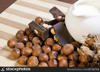 milk, hazelnuts and hazelnut chocolate on cutting board bamboo