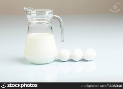 Milk in a glass jar and eggs on the table