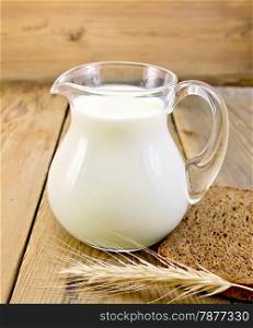 Milk in a glass jar with a slice of bread and spikelet on the background of wooden boards