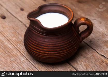 Milk in earthen jug on rustic woodtn table. Milk in jug