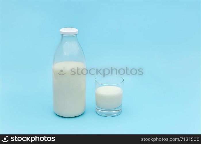 Milk in glass and bottle on blue background with copy space.. Milk in glass and bottle on blue background with copy space