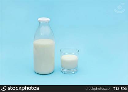 Milk in glass and bottle on blue background with copy space.. Milk in glass and bottle on blue background with copy space