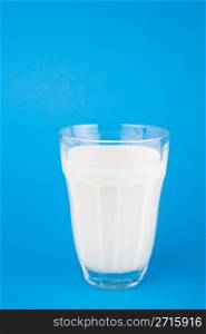 Milk in glass over blue background