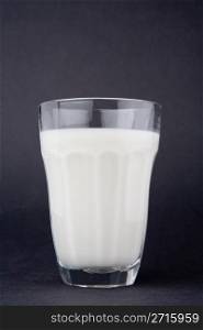 Milk in glass over dark grey background