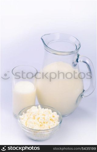 Milk in jug and glass and curds on white